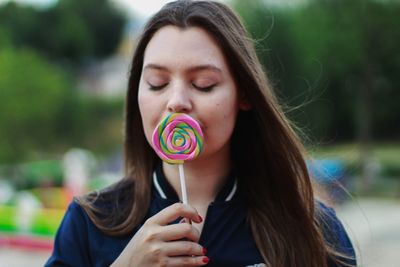 Close-up of woman with eyes closed holding lollipop 