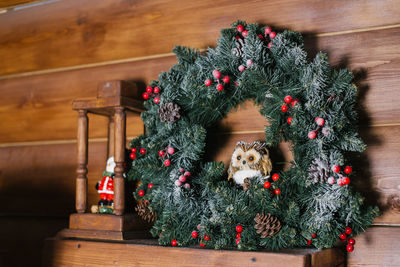 A christmas wreath with red berries is on the shelf and an owl toy