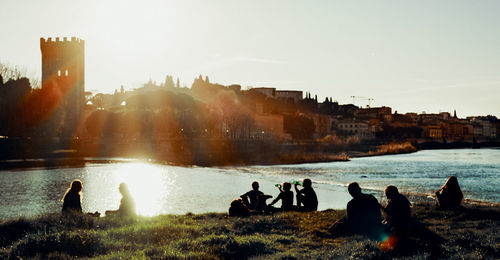 Group of people at beach against sky during sunset