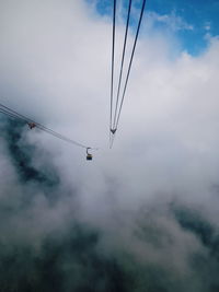 Low angle view of overhead cable cars against sky