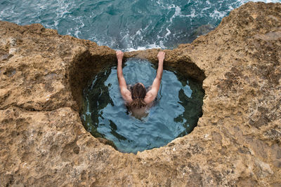 High angle view of person on rock by sea