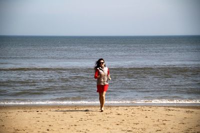 Full length of young woman walking at beach