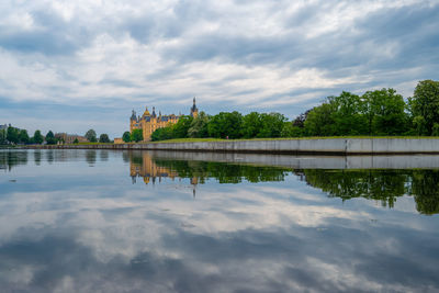 Reflection of building in lake against cloudy sky