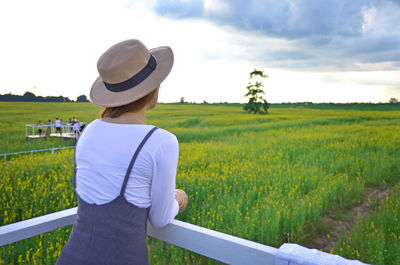Rear view of woman standing at observation point by farm