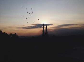 Low angle view of silhouette bird flying against sky at sunset