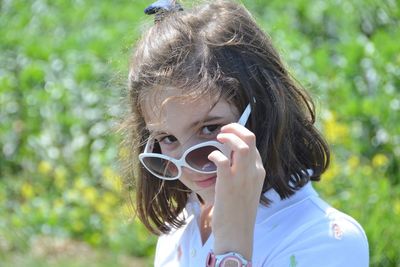 Portrait of girl wearing sunglasses standing on grassy field in park