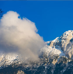 Low angle view of snowcapped mountains against blue sky