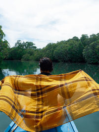 Rear view of man standing by swimming pool against sky