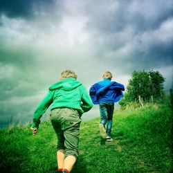 Man standing on grassy field against cloudy sky
