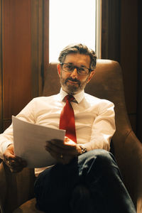 Portrait of confident mature lawyer with documents at legal office