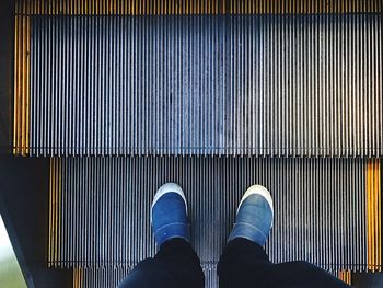 Low section of man standing on escalator