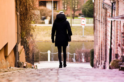 Rear view of woman walking on pathway amidst buildings