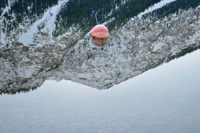 High angle view of buoy in lake with reflection on water during winter