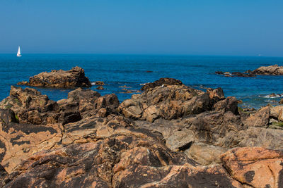 Rocks on beach against clear blue sky