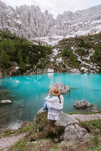 Woman sitting on rock by mountain