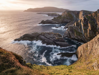 Scenic view of sea by mountains against sky