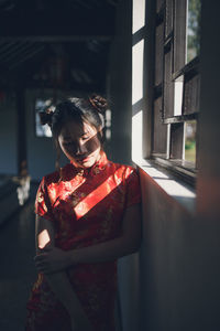 Young woman wearing traditional clothing while standing by window at home