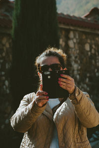 Mature woman in warm clothing using mobile phone while standing outdoors