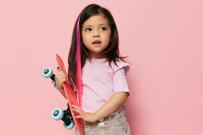 Portrait of smiling young woman holding heart shape against pink background