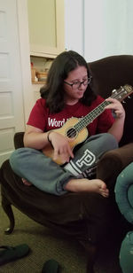 Young woman playing guitar at home