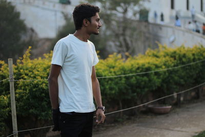 Young man looking away while standing by railing