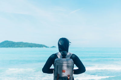 Rear view of man standing by sea against sky