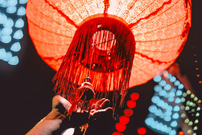 Cropped hand touching illuminated lantern