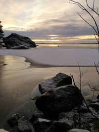 Rocks on beach against sky during sunset