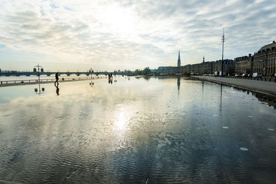 Garonne river by buildings against cloudy sky