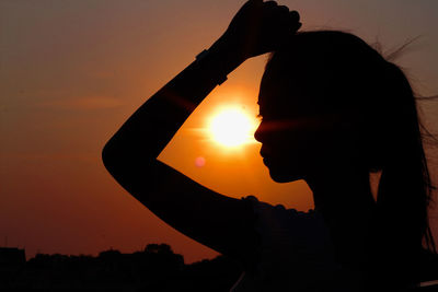 Silhouette woman standing against sun during sunset