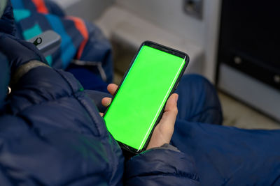 Back view of kid watch smart phone with green screen and browsing online in train