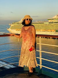 Young woman wearing sunglasses against boat in sea against sky