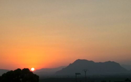 Scenic view of silhouette mountains against orange sky