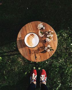 Low section of person standing by coffee cup on table