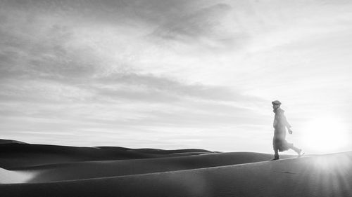 Side view of man standing on land against sky