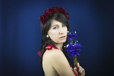 Portrait of woman holding rose against white background