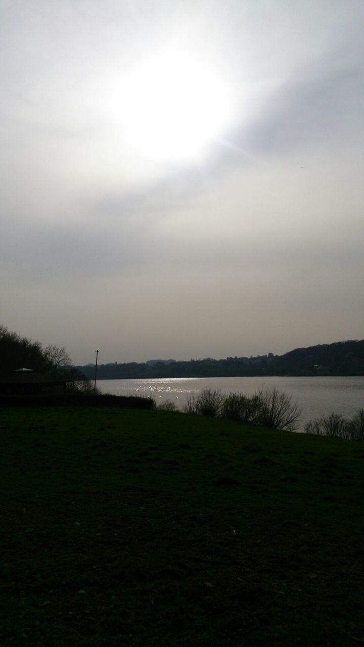 water, tranquil scene, tranquility, scenics, sky, beauty in nature, lake, grass, nature, sun, river, reflection, idyllic, sunlight, landscape, outdoors, field, silhouette, no people, tree