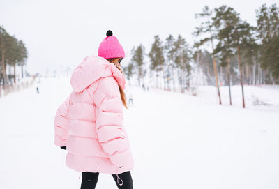 Rear view of woman walking on snow covered field