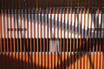 Shadows cast on a line of wooden poles creates a unique perspective on the walkway beyond. 