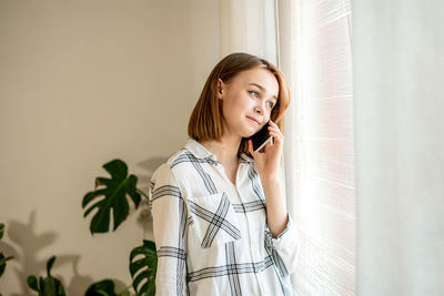 Happy pretty manager talking on mobile phone with client at home office.