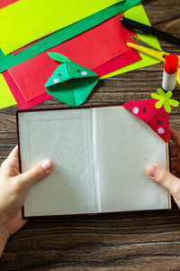 Cropped image of person holding paper painting on table