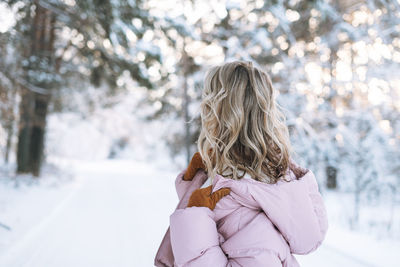 Rear view of woman standing on snow covered field