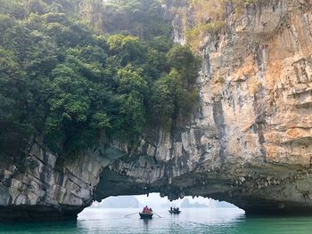 People in boat under rock formation over sea