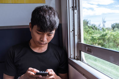 Young man using smart phone in train