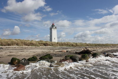 Lighthouse on beach against sky