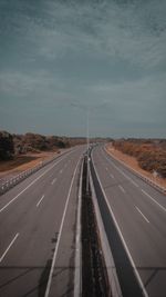 Empty road by highway against sky