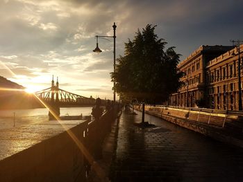 Bridge over river in city at sunset