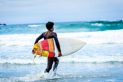 Man surfing in sea against sky