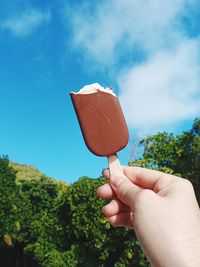 Midsection of person holding ice cream against sky