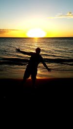 Silhouette of people on beach at sunset